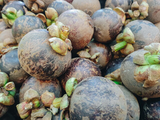 A close-up of a group of fresh mangosteens, showcasing their vibrant purple skin and green caps. Close-Up of Fresh mangosteens background texture