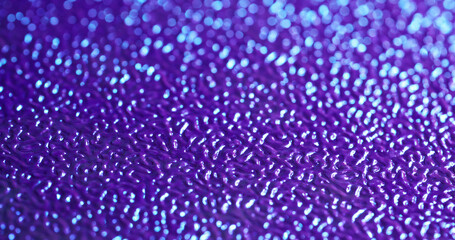 Blurred texture. Plastic sheet. Violet patterned artificial leather relief with changing lighting. Decorative bright flare skin background.
