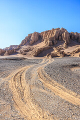 Desert sand road and mountain natural landscape in Xinjiang. Road trip in no man's land. Famous Dahaidao desert gobi scenery in China.