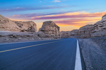 Asphalt road and mountain natural landscape at dusk in Xinjiang. Road trip in no man's land. Famous Dahaidao desert gobi scenery in China.