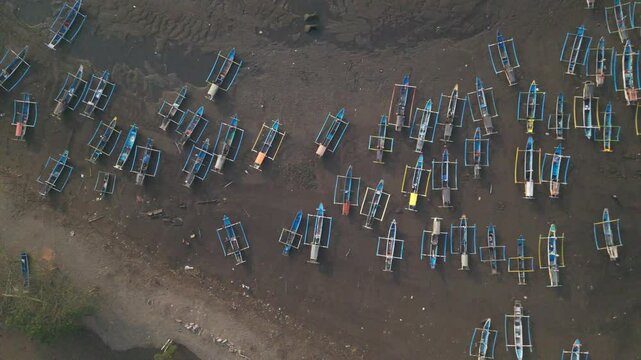 Drone footage over Papuma beach with clean green water and fishing boats sailing from shoreline