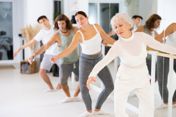 Fototapeta premium Women and men training in ballet class with other dancers
