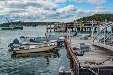 Small Lobster Boats at a New England Dock:  Lobster holding crates sit in the water and on a floating dock where small fishing boats tie up on a cloudy afternoon in Maine.
