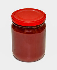 A jar of red sauce is sitting on a white background