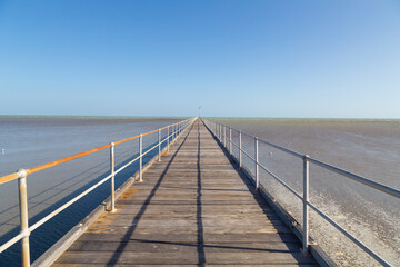 Obraz premium A wooden pier that was once one of the longest loading piers in the Southern Hemisphere because of the gradual slope of the beach, and it is now a historic pier in Port Germein in South Australia.