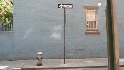 New York City oneway crossroad, Minetta street intersection one way arrow road sign. Manhattan Greenwich Village residential building architecture, NYC, United States. Blue brick wall, fire hydrant.