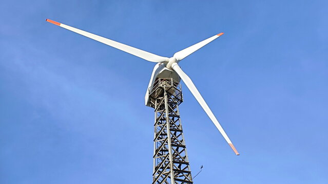 Isolated wind turbine lattice tower in blue sky - Powered by Adobe