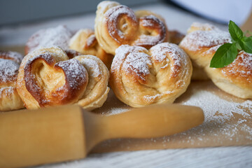Homemade buns with sugar powder and wooden rolling pin. Selective focus.