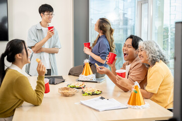 Smiling, cheerful diverse Asian employees enjoy drinks and conversations while celebrating their successful project at an office party. team building, celebration, office party, teamwork