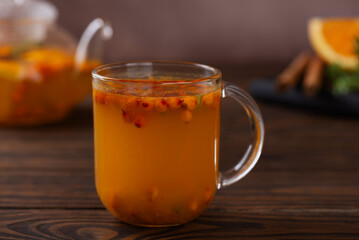 Hot sea buckthorn tea with orange, ginger, honey, thyme and cinnamon in cups on a brown background. Herbal vitamin c tea.