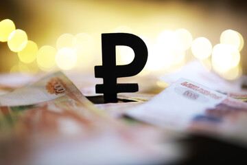 Russian Ruble Currency Symbol with Blurred Banknotes and Gold Bokeh Lights in Background