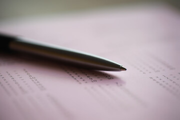 Close-Up of Pen on a Pink Form with Blurred Numbers in Background - Stock Photography for Business and Education