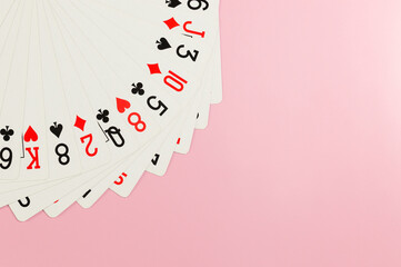 Top view of playing cards on pink background. Board game, poker. Copy space, flat lay.