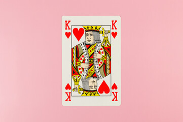 Top view of playing cards on pink background. One king card, board game, poker. Copy space, flat lay.