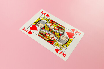 Top view of playing cards on pink background. One king card, board game, poker. Copy space, flat lay.