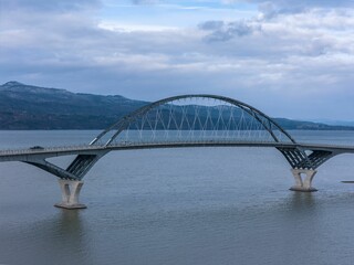 Obraz premium Modern arch bridge over a serene lake.
