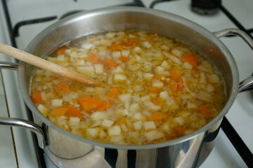 Cooking vegetable soup in a stainless steel metal pot.