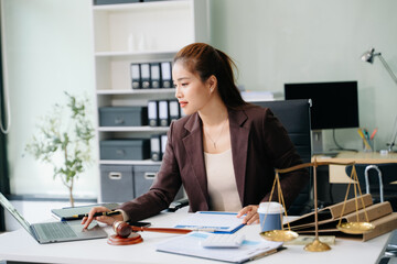 Confident lawyer working on legal analysis at a modern office desk, featuring scales of justice, a...