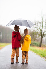 two little girls under an umbrella in the rain