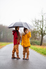 two little girls under an umbrella in the rain