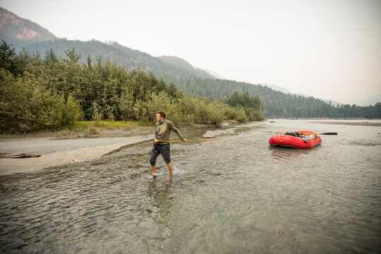 Rafting guide walks his raft up a shallow river channel.