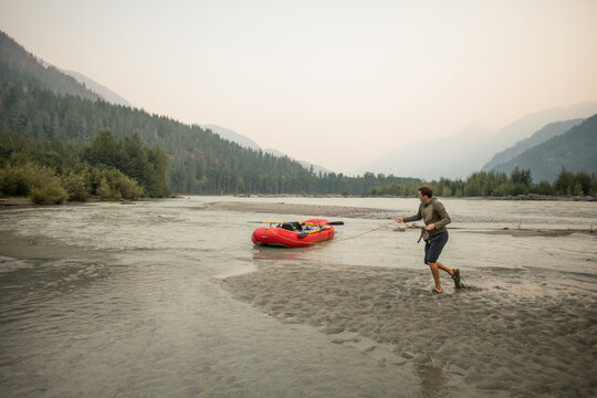 Raft guide walks his raft down to his campsite on the Squamish River.