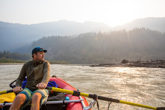 Man looks thoughtful while rowing raft on scenic river