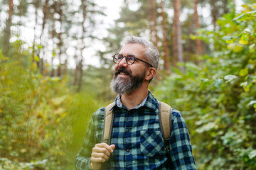 Handsome man standing in the middle of nature, enjoying peaceful atmosphere of the forest,...