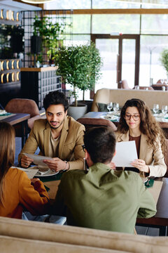 Coworkers with menu talking to each other at restaurant