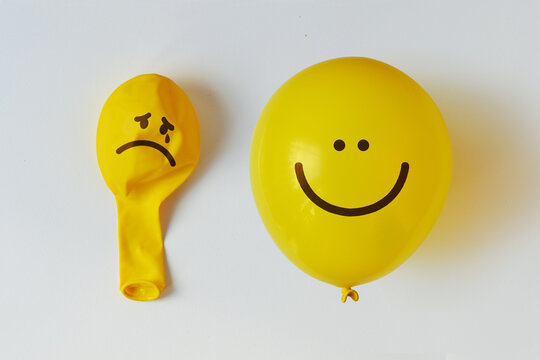 Deflated ballon with sad face and inflated balloon with happy face - Concept of mental health