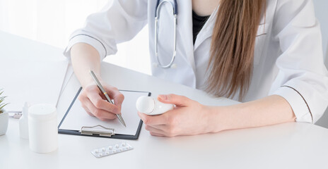 Mid section of female doctor writes prescription to patient at worktable. Panacea and life save.