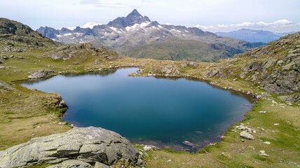 Naklejka premium A serene mountain landscape featuring a calm lake surrounded by rocky terrain and distant peaks under a clear sky.