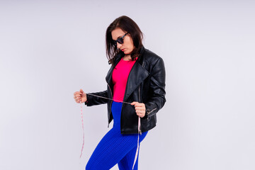 Pretty female with excess weight in sporty top measuring waist over white yellow background