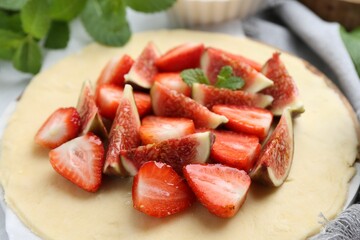 Making galette. Fresh dough, strawberries, figs and mint on table, closeup