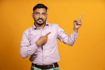 Indian man on isolated background pointing towards the empty space for advertising