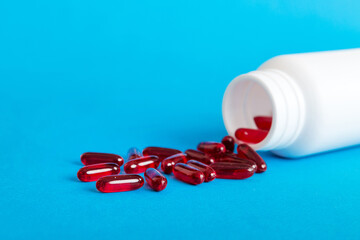 Red pills spilled around a pill bottle. Medicines and prescription pills flat lay background. Red medical capsules