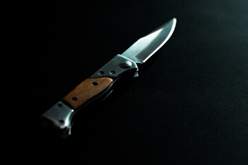 Folding knife with wooden handle on dark background
