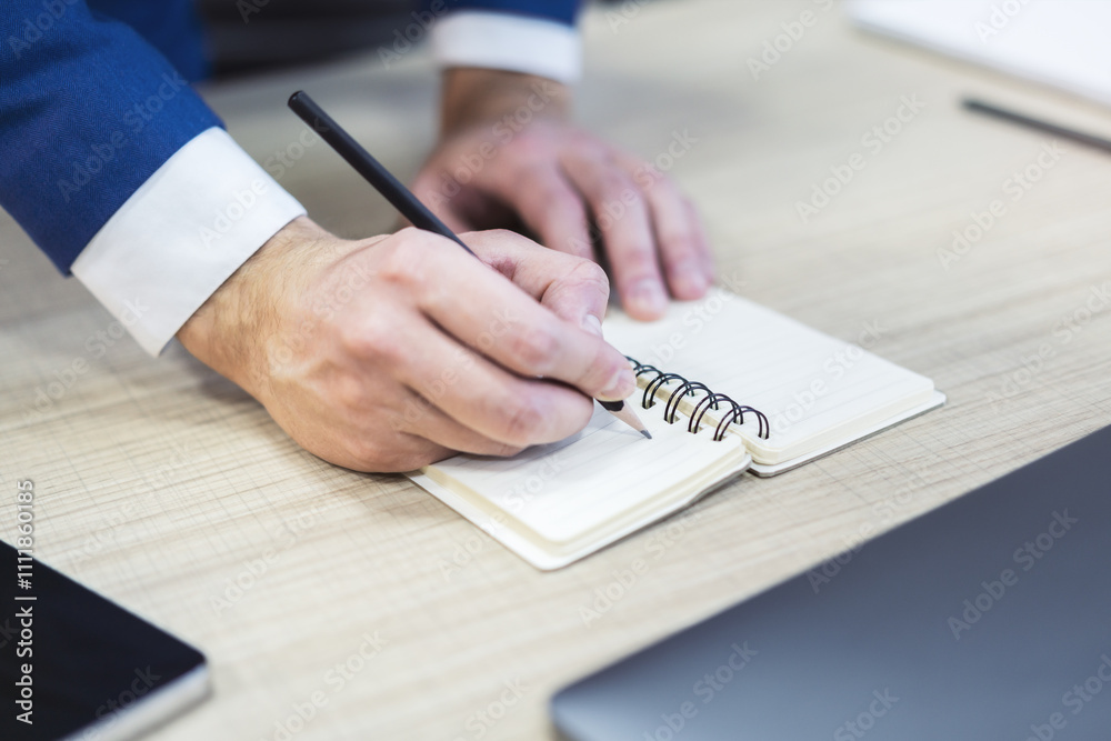 Aufkleber detailed view of a man's hand jotting notes in a notepad, with a blurred background