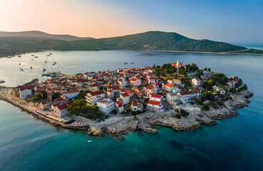Primosten, Croatia - Aerial view of Primosten peninsula and old town on a sunny summer morning in Dalmatia, Croatia. Blue and golden sky at sunrise on the Adriatic sea coast
