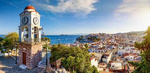 Panoramic sunset view of the cityscape of Skiathos town, Sporades, Greece, with the tower of Agios...