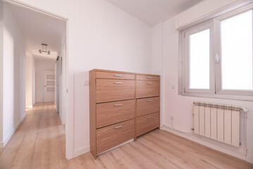 Corner of a bedroom with a wooden shoe rack and white aluminum radiators