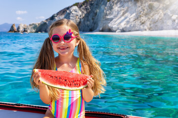 Summer travel concept with a cute little girl holding a red water melon slice in front of turqouise...