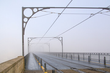 Fototapeta premium Oporto, Portugal - November 8, 2024 : Famous bridge Ponte dom Luis in the morning fogabove old town at river Duoro, Portugal