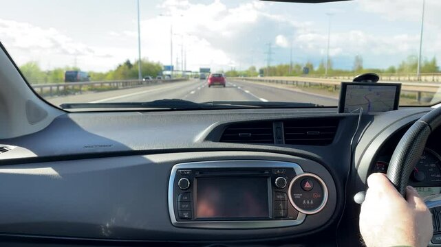 Driving on a highway in England, car dashboard and windscreen view, selective focus, blurred background.