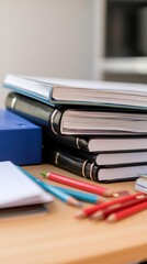 A stack of binders and stationery on a desk for organizational purposes.