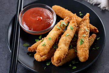 Breaded Torpedo shrimps on black slate background