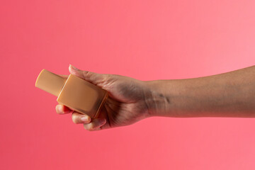 Fototapeta premium Cosmetic cream tube in womans hand on pink background 