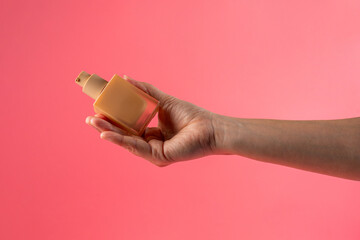 Cosmetic cream tube in womans hand on pink background 