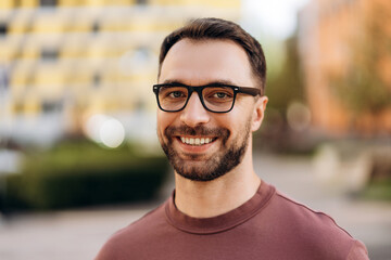 Portrait of happy, smiling bearded man wearing eyeglasses, looking at camera closeup