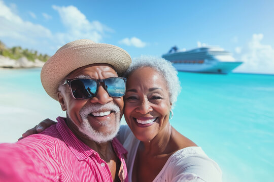 A joyful senior Black couple taking a selfie on a tropical beach with turquoise water, a cruise ship in the background, and clear blue skies